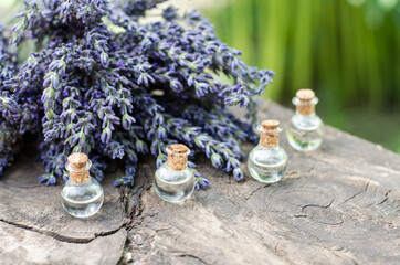 Lavender oil in small bottles on a wooden table. Lavender oil and lavender bouquet