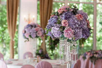 A beautiful floral arrangement of pink and lilac flowers is on the table in the restaurant. Close-up