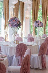 A beautiful floral arrangement of pink and lilac flowers is on the table in the restaurant.