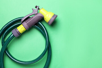 Watering hose with sprinkler on green background, top view. Space for text
