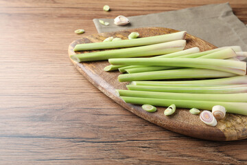 Board with fresh lemongrass stalks on wooden table. Space for text