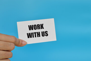 Hand holding white card written with phrase WORK WITH US