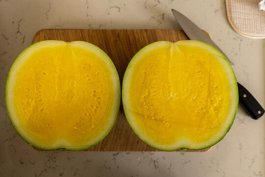 Cut yellow watermelon on a board with knife