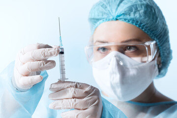 Close up view of doctor with the syringe of covid vaccine on blue back