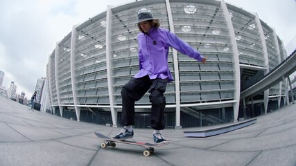 Sporty man making kickflip outdoor. Active hipster riding skateboard outside.