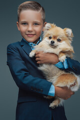 Little boy with fluffy dog posing against gray background