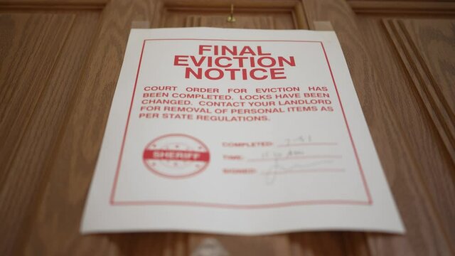 A dramatic low angle view of an eviction notice on a home's front door. The eviction moratorium during the coronavirus pandemic of 2020 came to an end in late summer 2021. Sign then gets ripped down. 