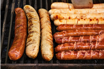delicious variety of sausages on the grill grill over an open fire. Food festival in the city on the street. sausages are grilled at the food court barbecue for a summer picnic. Grilled Munich sausage