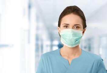 Fototapeta na wymiar Female doctor with face mask on hospital background