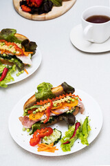Banh mi sandwiches with various stuffing and cup of tea. Traditional vietnamese breakfast. Trendy still life in light colors.