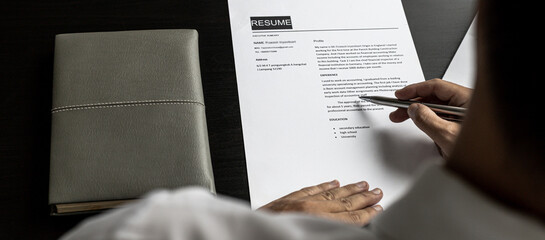 Managers are reviewing resumes of candidates who are interviewing for vacancies, he is looking at personal information and competence and education information to be considered for employment.