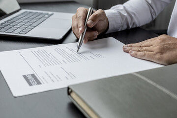 Managers are reviewing resumes of candidates who are interviewing for vacancies, he is looking at personal information and competence and education information to be considered for employment.