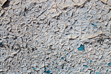The texture of peeling gray paint on a concrete wall