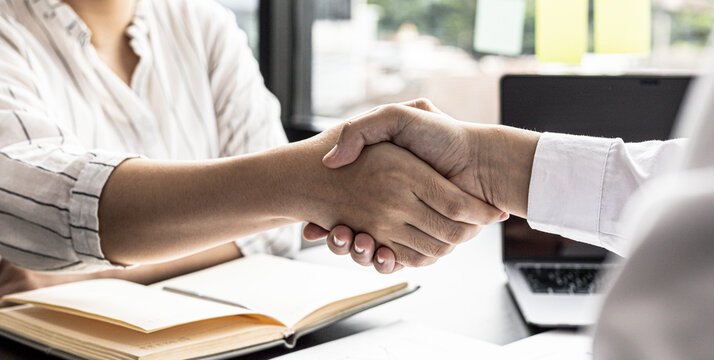 Two businessmen shake hands, they are business partners to open a company together, they attend a brainstorming meeting to manage sales growth and join hands after business talks. Management concept.
