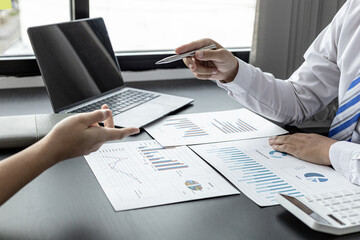 A businessman holding a pen and pointing to a businesswoman, he is explaining the problem of falling sales to business partners in detail to make a decision. Company management concept.