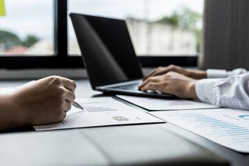 Fototapeta premium Close-up businesswoman holding a pen pointing to a bar graph document of company financial data, she is reviewing the company's monthly financial documents. Finance concepts and money management.