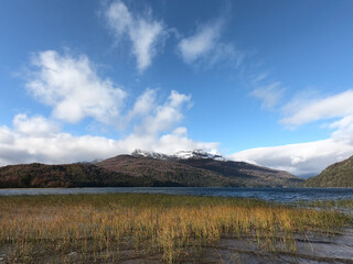 Alpine landscape. Beautiful view of Lake Falkner, the shore, reeds and mountains and forest in autumn, under a blue sky.