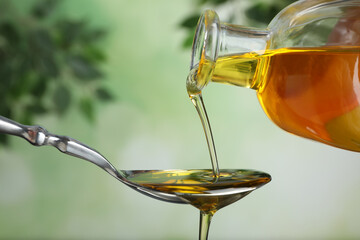 Pouring hemp oil into spoon on blurred background, closeup