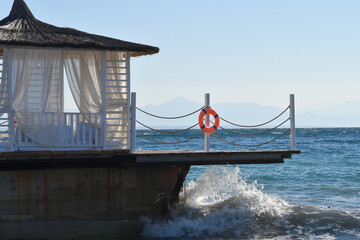 Sea waves breaking at the wooden pier at sunset.