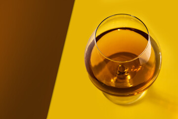 Cognac or whiskey drink on yellow and brown background. Copy space