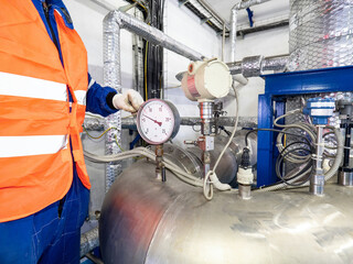 Man worker at chrome pipe with pressure and temperature control.