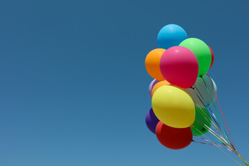 Bunch of colorful balloons against blue sky. Space for text