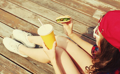 Portrait of young woman with burger and cup of juice fast food in the city