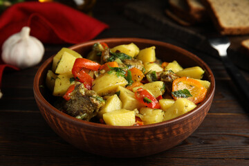 Tasty cooked dish with potatoes in earthenware on wooden table