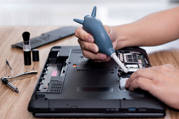 A man hold air pump to blow dust in repair laptop computer and tool computer repair on the table