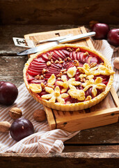 Pie with plum and nuts. Short crust pastry, chopped plums. Side view. Wooden background.