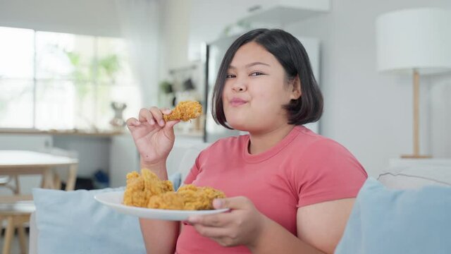 Portrait of Asian young oversize big women eat unhealthy food at home.