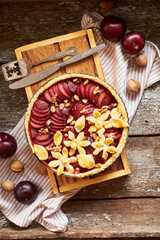 Pie with plum and nuts. Short crust pastry, chopped plums. Top view. Wooden background.