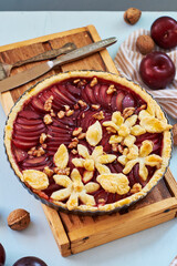 Pie with plum and nuts. Short crust pastry, chopped plums. Side view. Blue background.