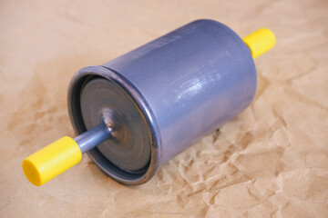Auto parts. Car fuel gasoline filter. Close-up photo of the filter on craft paper.