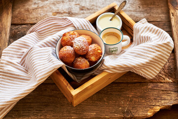 Round curd donuts. Sweet white sauce, fried balls. Side view. Coffee, rustic.