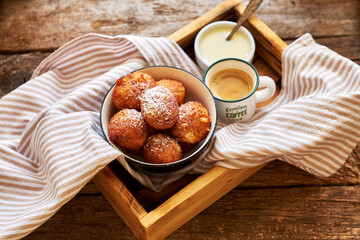 Round curd donuts. Sweet white sauce, fried balls. Side view. Coffee, rustic.