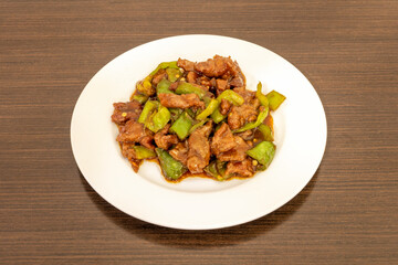 Beef stew with green peppers cooked by a Chinese chef in a Chinese food restaurant for home delivery