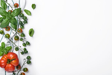 Fresh cherry tomato branches, basil leaves, napkin, pepper and pepper mill on a white background. Food cooking background and mock up.