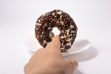 female hand with a chocolate donut on white background.