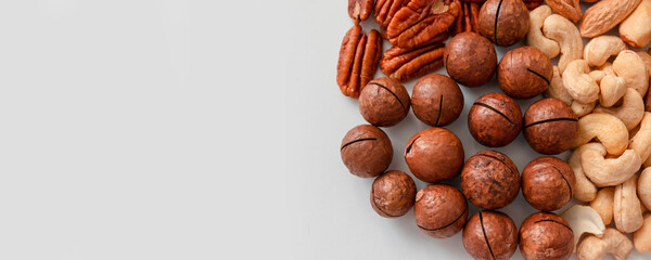 Top view of pecans, brazil nuts, cashews, almonds and macadamia nut. Proper nutrition composition of assorted nuts pattern vertical photo on gray background. Flat lay, empty place for text