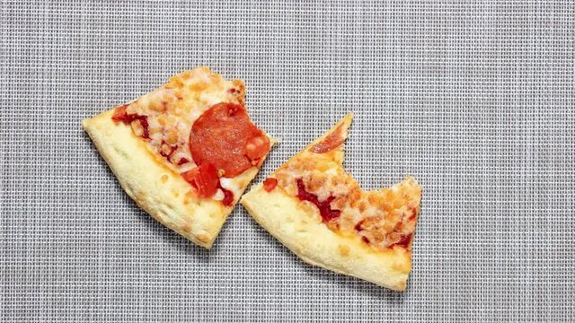 Stop motion animation. Two slices of pizza, which is gradually bitten off. Close-up, selective shot.