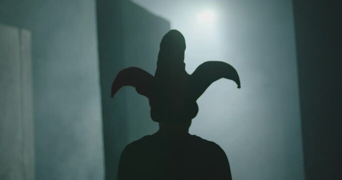 Evil clown , jester or joker running and jumping inside dark maze . Mystic video of buffoon in labyrinth . Fool or joker escape . Vision of horror dream . Shot on ARRI ALEXA Cinema Camera in slow .