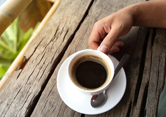 Men hands holding cups of coffee on rustic wooden table background.