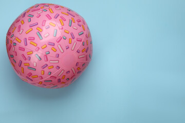 Pink beach ball on light blue background, top view. Space for text