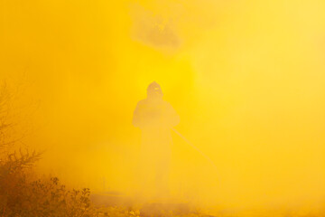 Forest fires, silhouette of a firefighter in fiery smoke extinguishes the forest with water,...