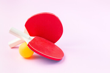 Children mini rackets ping pong or table tennis and orange ball on pink background, horizontal,...