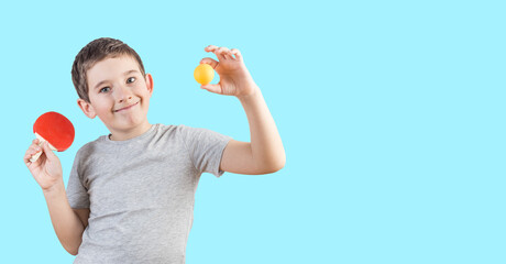 Cute nine years old boy in a gray t-shirt with mini table tennis racket and orange ball. Mini ping pong table game - obrazy, fototapety, plakaty