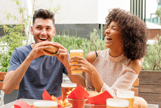 Happy hungry couple enjoying hamburgers and beers - Powered by Adobe