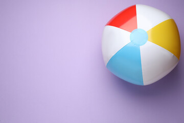 Fototapeta premium Colorful beach ball on violet background, top view. Space for text