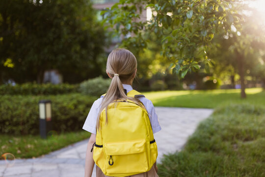 Back to school. Little girl with yellow backpack from elementary school outdoor. Kid going learn new things 1th september after end Coronavirus covid-19 quarantine and self isolation 